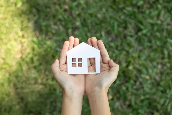 stock image Top view hand hold house icon, presenting house loan opportunity as part of real estate sales. Promoting eco-smart homes, embodying vision for sustainable bright future nurturing with nature. Gyre