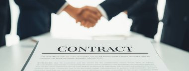 Yönetim kurulunda iki yönetici el sıkışıyor, iki şirketi birbirine bağlıyor. El sıkışmak iş ortaklığını ve işbirliğini simgeler. Şirket kazancı ve birleşme konsepti. Kurnaz.