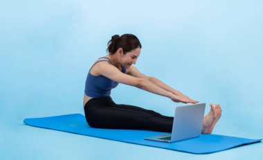 İnternetteki videodan alınan talimatlara göre spor kıyafeti giymiş genç Asyalı bir kadın spor egzersizinden önce geriniyor. Sağlıklı atletik bir kadınla vücut egzersizi izole bir zeminde ısınıyor. Kuvvetli