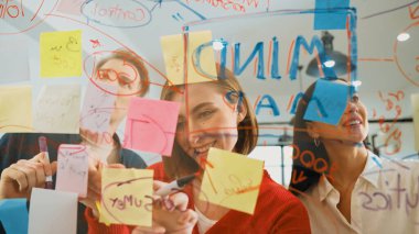 Yaratıcı iş adamları, modern toplantı odasındaki renkli yapışkan notları yazarak projeyi başlatma ve pazarlama fikrini paylaşıyorlar. Birlikte çalışmak. Tertemiz..