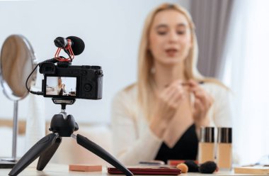 Sosyal medya için güzellik ve kozmetik video içeriği hazırlayan bulanık genç bir kadın. Güzellik etkileyicisiyle odaklanmış kamera ekranı izleyicilere ve takipçilere güzellik hizmetinin nasıl uygulanacağını gösteriyor. Blithe