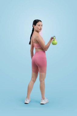 Dinç, enerjik bir kadın izole edilmiş arka planda ağırlık kaldırma egzersizi yapıyor. Genç atletik Asyalı kadın dayanıklılığı ve dayanıklılık eğitimi rutin vücut egzersizi..