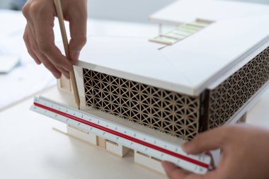 Modern ofiste cetvel ve mimari ekipmanlar kullanarak ev modelini ölçen profesyonel mimar elin yakın çekimi. Yaratıcı iş tasarımı konsepti. Eline odaklan. Tertemiz..