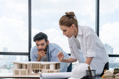 Akıllı beyaz mimar mühendis takımı ev modelini ölçmek için birlikte çalışıyor. Bir grup profesyonel iç mimar tasarım inşaatı hakkında fikir paylaşımı ve beyin fırtınası yapıyor. İzleme.