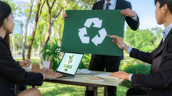 Group of businesspeople meeting at outdoor office in the nature planning and brainstorming on recycle strategy for greener environment by reducing and reusing recyclable waste. Gyre
