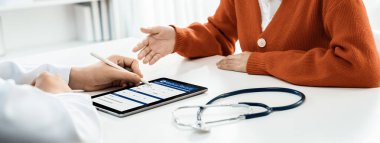 Klinikteki ya da hastane ofisindeki doktor randevusuna katılan hasta, tıbbi tedavi seçeneklerini tartışıyor ve muayene sonuçlarını ya da hastalıkla ilgili tıbbi kayıtları açıklıyor. Panorama Katı