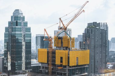 Dış gökdelenlerin, kule vinçleri olan inşaat alanının görüntüsü. İnşaat halindeki şehir manzarası. Binanın tadilatı için çalışan vinçler var. Mavi gökyüzü arka planı. Mimari. Süslü.