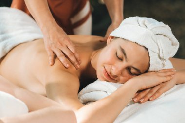 Güzel genç bir kadın, profesyonel masözden kaplıca yatağına sırt masajı almış. Çekici bir kadın masaj terapistinin yetenekli elleriyle derin bir şekilde rahatlar. Doğayla çevrili. Huzur.