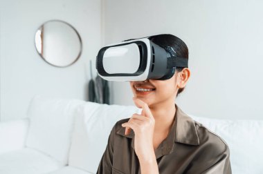 Sanal gerçeklik gözlüğü kullanan genç bir kadın online alışveriş deneyimi için evde. Sanal gerçeklik VR yeniliği dijital eğlence yaşam tarzı için optimize edildi.