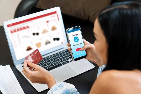 Young woman order or purchase product on internet using laptop and make transaction payment by smartphone. Online shopping lifestyle with credit card via internet banking on mobile application. Blithe