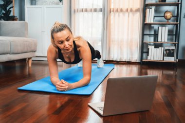 Sportif ve sportif son sınıf öğrencisi bir kadın, emekli olduktan sonra sağlıklı yaşam biçimi konsepti olarak ev egzersizinde online fitness videosu izlerken spor paspası takıyor. Etki