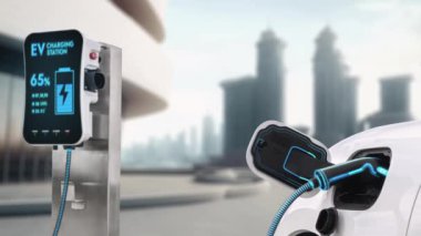 Elektrikli araba şarj istasyonuna bağlanır ve şehrin arka planında gelişmiş EV şarj cihazıyla şarj edilir. Gelecekteki yenilikçi çevre dostu enerji sürdürülebilirliği CO2 emisyonunu azaltmak için. İnceleyin