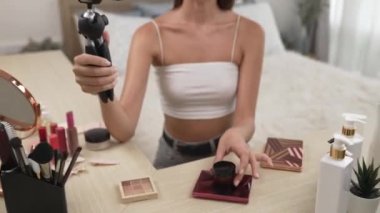 Sosyal medya için güzellik ve kozmetik video içeriği hazırlayan genç bir kadın. Güzellik blogcusu kameraya gülümserken seyircilere ve takipçilere güzellik bakımını gösteriyor. Düzenle