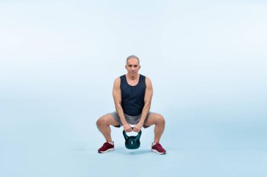 Vücut uzunluğu tam, atletik ve sportif yaşlı bir adam izole edilmiş arka planda vücut çalışması için kettlebell ile hiçbir şey yapmıyor. Emeklilikten sonra sağlıklı, aktif bir fiziğe ve vücut bakımına sahip. Etki