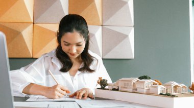 Mimari model, dizüstü bilgisayar ve planla not alırken kalem kullanarak ev modelini ölçen genç ve güzel mimar mühendisinin portresi. Yaratıcı iş tasarımı konsepti. Yönlendirici.