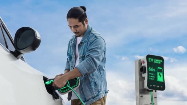 アジアの男は充電ステーションから電気自動車にスマートEv充電器を挿入します Evカーコンセプトによる持続可能でクリーンな輸送技術のための将来の代替エネルギー利用 パーセント — ストック動画