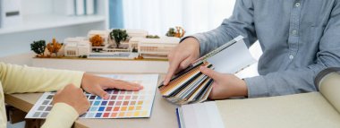 İç mimar takımı, proje yöneticisine renk örnekleri ve mimari modeli toplantı masasında sunar. Yaratıcı çalışma ve tasarım konsepti. Eline odaklan. Değiştirilmiş.