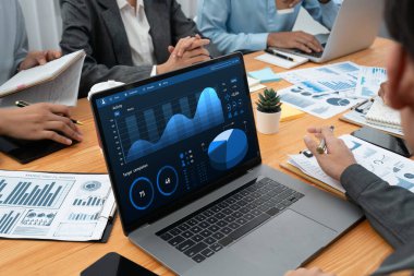 Çok ırklı analist ekibi toplantı masasındaki finansal verileri analiz etmek için BI Fintech yazılımı kullanıyor. Finansal konsol veri ekranında pazarlama göstergesi için analiz edilmiş grafikle birlikte. Uyum