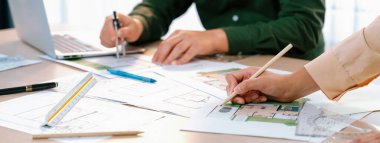 Profosyonel mühendisin, plan, dizüstü bilgisayar ve mimari ekipmanların etrafa saçıldığı toplantı masasının planlarını ölçmek için bölücü kullandığı kırpılmış bir görüntü. - Yakın çekim. Tanımlama.