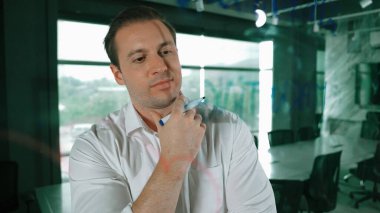 Akıllı iş adamı cam tahtanın önünde bir proje başlatmayı düşünüyor. Gülümseyen erkek proje yöneticisi yaratıcılık pazarlama stratejisini gösteren renkli yapışkan notlara bakıyor. Yönlendirici.