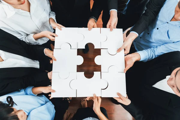 Top view multiethnic business people holding jigsaw pieces and merge them together as effective solution solving teamwork, shared vision and common goal combining diverse talent. Meticulous