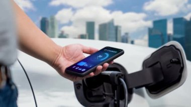 EV akıllı telefon uygulamasında EV akü durumu. Kamu şarj istasyonundan şarj olurken. EV arabaların yenilikçi teknolojik gelişimi ve alternatif enerji kullanımı. İnceleyin