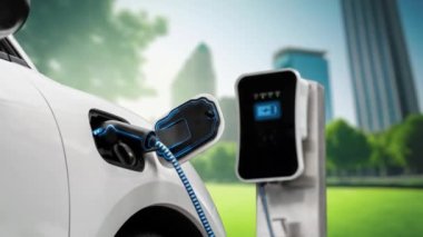 Yeşil Şehir Parkı 'ndaki ekolojik temiz enerji şarj istasyonundan gelen fütürist akıllı EV şarj aletinin şarj ettiği elektrikli araba. Alternatif enerji kullanan gelecekçi elektrikli araba. İnceleyin