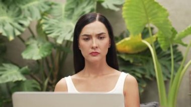 Stresli kadın, yeşillik arka planında internet üzerinden çalışırken yorgun ve hayal kırıklığına uğramış hissediyor. Bunaltıcı ve zorlu uzak çalışma görevleri. Blithe