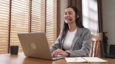Kadın çağrı merkezi operatörü ya da müşteri hizmetleri çalışanı, müşteriye yardım etmek için kulaklıkla konuşurken çalışma alanı üzerinde çalışıyor. Profesyonel modern iş hizmeti. Blithe