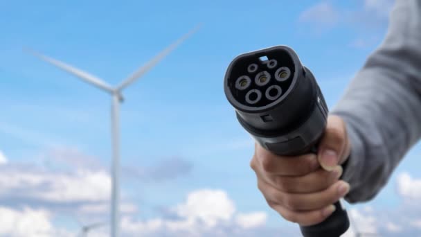 カメラの前に置くフォーカスEv充電器は未来的なスマートなデジタルEv電池の状態ホログラムを表示します 風力タービンから再生可能エネルギーを利用したEvカーチャージャー パーセント — ストック動画