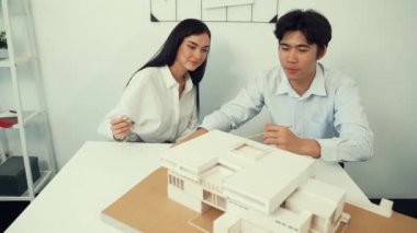 Becerikli mimari mühendisi ekip ölçümü ve ev modeline birlikte çalışırken karar verme ve toplantı odasındaki bina yapısı ve planlarla ilgili tartışmalar. Tertemiz..
