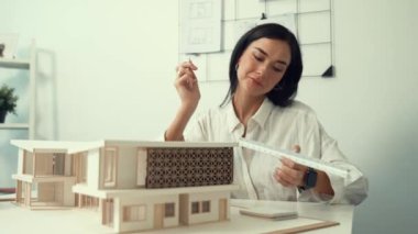 Profesyonel mühendis mimarın üçgen ölçekli ölçü evi modelini kullanarak modern ofisteki yapı uzunluğunu not alarak yakınlaşması. İş tasarımı. Tertemiz..