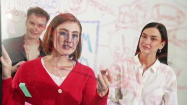 Başarılı proje yöneticisi fikrini cam tahtaya sunup yazarken aynı zamanda meslektaşına yaratıcı iş toplantılarında pazarlama stratejisini soruyor. Birlikte çalışmak, beyin fırtınası yapmak. Tertemiz..