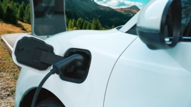 Tepe yolundaki şarj istasyonunda elektrikli arabanın çevresel farkındalığı için yenilikçi bir kavram. EV araba temiz çevre için yenilenebilir enerjiden güç alıyor.