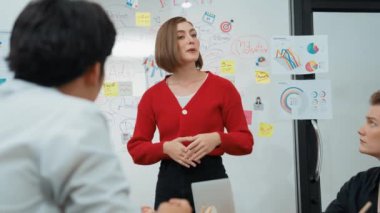 Genç ve güzel profesyonel iş kadını, yaratıcı iş toplantısında yakışıklı yönetici dinlerken zihin haritalama ve istatistiksel grafik kullanarak pazarlama fikrini kendine güvenle sunuyor. Tertemiz..