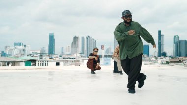 Profesyonel break dans takımı çatıda çok kültürlü arkadaşlar varken break dans alıştırması yapıyor. Genç modern dans grubu hip hop hareketi yapıyor. Tarz, moda, aksiyon. Açık hava sporu 2024. ÇalışmaComment.