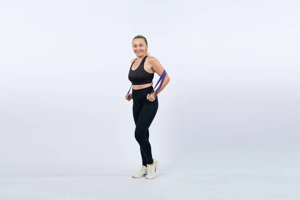 Full body length shot athletic and sporty senior woman with fitness resistance band on isolated background. Healthy active physique and body care lifestyle after retirement. Clout