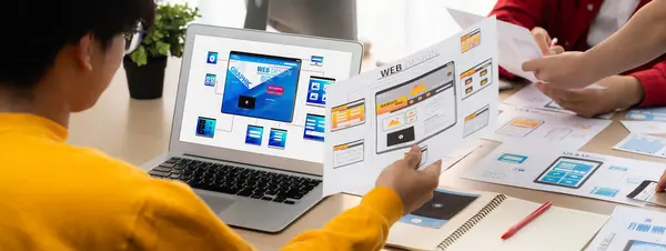 Panorama banner of startup UX developer or company employee design user interface or UI prototype for mobile application or website software with software display on laptop monitor in office. Synergic