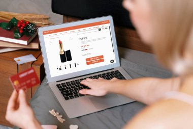 Genç bir kadın internet bankacılığı için kredi kartıyla dizüstü bilgisayar kullanıyor. Evinde online ödeme kapısı ile E ticareti yapıyor. Banka kartıyla modern ve kullanışlı online alışveriş. Blithe