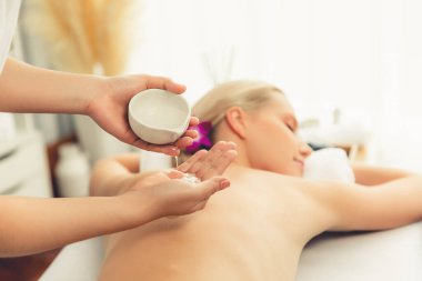 Masör elleri kadının sırtına aroma yağı döküyor. Masözler lüks otellerdeki kaplıca salonundaki müşteriler için yağ masajı prosedürü hazırlıyorlar. Aroma yağı vücut masajı konsepti. Sessiz.