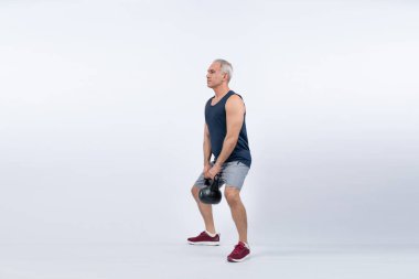 Vücut uzunluğu tam, atletik ve sportif yaşlı bir adam izole edilmiş arka planda vücut çalışması için kettlebell ile hiçbir şey yapmıyor. Emeklilikten sonra sağlıklı, aktif bir fiziğe ve vücut bakımına sahip. Etki