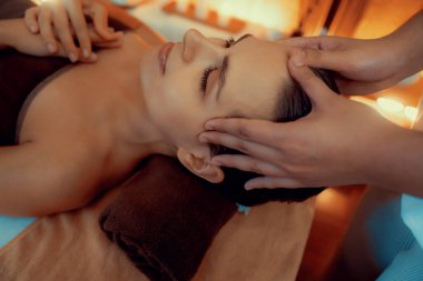 Kafkasyalı kadın stres önleyici kafa masajını yapmaktan ve lüks otel veya otelde sıcak mum ışığında yüz güzelliğini şımartmaktan zevk alıyor. Sessiz.