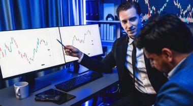 İki borsa simsarı dinamik yatırım grafiğini tartışıyor, yüksek kar eğilimli döviz borsası. İş yerindeki neon ışıkta finansal fayda verileri monitörde gösteriliyor. Satılabilir.