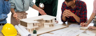 Mimari takım analizi ve ev modeli, plan ve mimari ekipmanlarla toplantı masasında ev inşaatı hakkında beyin fırtınası. Yaratıcı tasarım ve takım çalışması. Filizlenen.