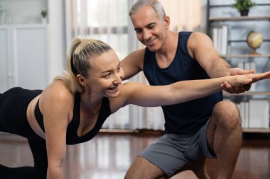 Spor giyim sektöründe aktif olan mutlu çift destekleyici ve evde yoga duruşunda birlikte yardımcı oluyorlar. Yoga egzersizi yapan sağlıklı bir erkek ve kadın yaşam tarzı. Etki