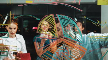 Yetenekli erkek lider, istatistik grafiğini uzman yatırımcılara açıklıyor. Akıllı iş adamı sunar, finans planlarını gece ofisindeki cam duvardaki yatırımcılara gösterir. İş konsepti. İzleme