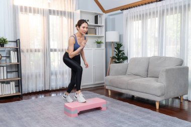 Enerjik bir kadın evde egzersiz yapıyor, kardiyo aerobik egzersizi yapıyor. Genç atletik Asyalı kadın mahareti ve dayanıklılık antrenmanı ev ödevi rutin konsepti olarak..