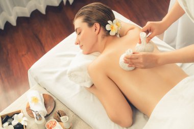 Sıcak bitkisel top spa masaj vücut tedavisi, masör kadın vücuduna nazikçe şifalı bitki torbası bastırıyor. Aromaterapi dinlenme sükuneti ve sükuneti kaplıca salonundaki atmosferi aydınlatıyor. Sessiz.