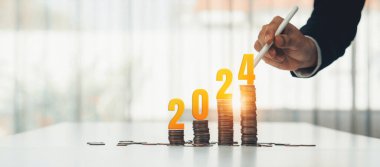 Büyüyen madeni para yığını iş yatırımını ve ekonomik büyümeyi simgeliyor. Finansal hedefe ulaşmak ve 2024 yılına maksimum kar sağlamak için finansal planlama yapan iş adamları. Kurnaz.