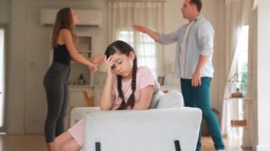 Sinirli ve mutsuz genç bir kız oturma odasında ebeveyninin tartışması yüzünden gerginliğin ortasında kanepede oturuyor. Sağlıksız ev hayatı ve travmatik çocukluk depresyona dönüşür.